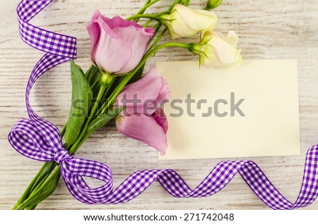 Empty postcard with flower and purple ribbon on wooden background