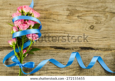 Empty wooden background with colorful flowers and blue ribbon