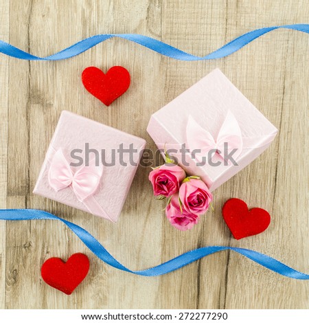 Gift box with rose flower, heart and ribbon on wooden background