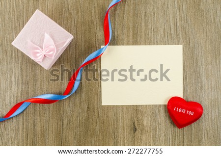 Empty card with heart and gift box on wooden background