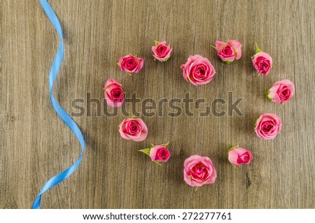 Heart shaped rose flower and ribbon on wooden background