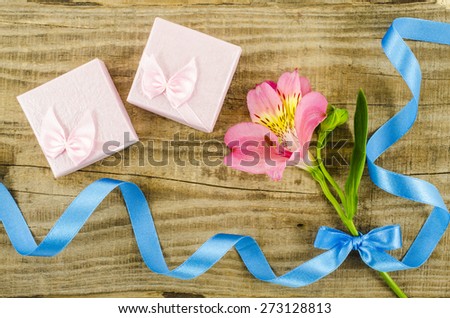 Gift boxes with flower and ribbon on wooden table