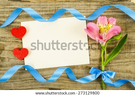 Colorful flower with ribbon and empty card on wooden table