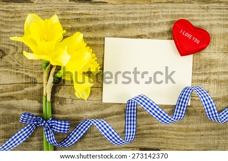 Empty card with flower and ribbon on wooden background