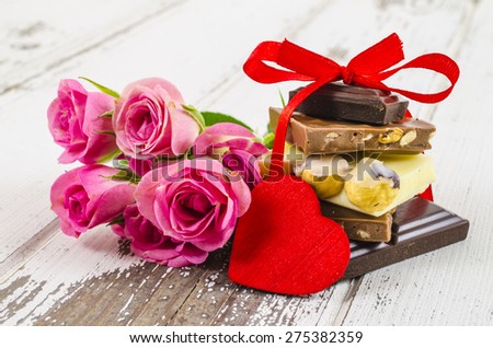 Chocolate with ribbon and flower on wooden background