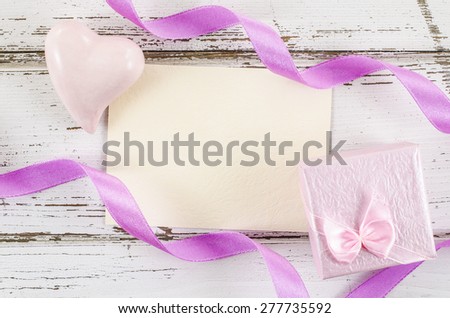 Empty card with gift box and heart on wooden table