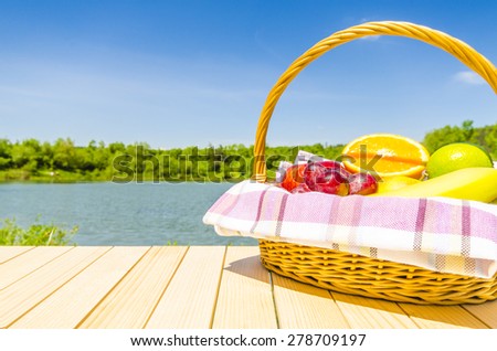 Picnic basket full of fresh fruits on wooden table