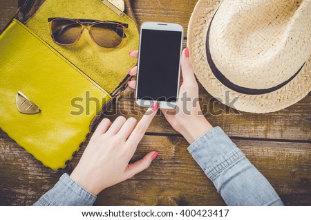 Female hand using mobile phone over old wooden table
