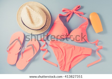 Pink swimsuit with beach accessories on blue background