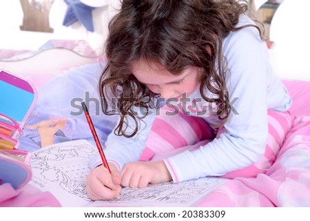 young girl writes/draws in a book on her bed