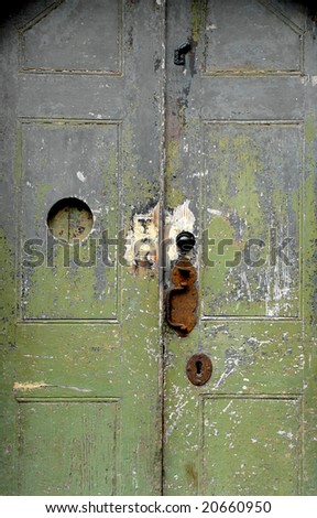 vintage door where paint is fading from green to grey with rusty handle