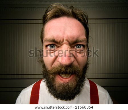angry man with beard screws his face up with emotion