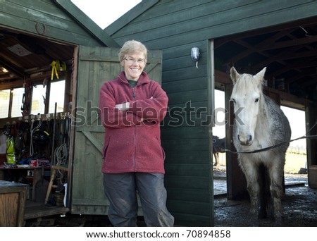 Mature woman spending time with her horses in their stable