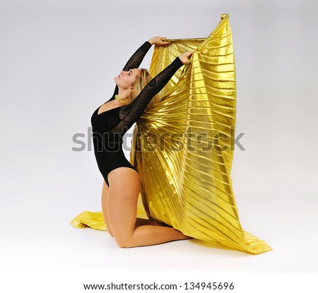 Dancer with golden wings on a grey background.Gymnast.Oriental dance.Plastic arts of human body.