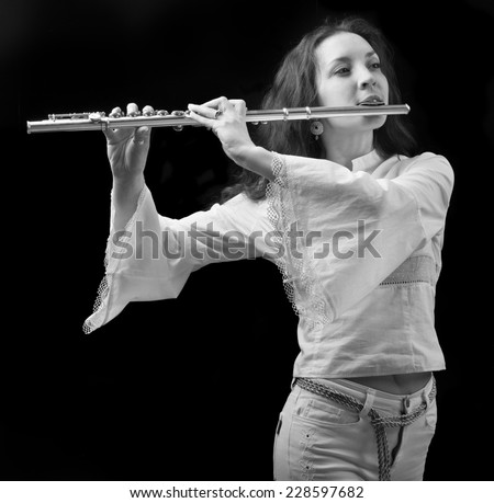 girl plays the flute on a black background.black-and-white photo