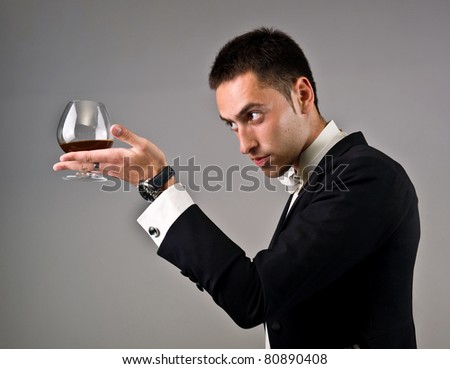 emotional man in a suit with glass of wine on a grey background