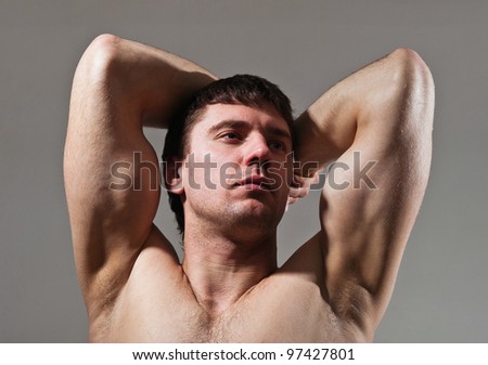 real man.figure of an athlete on a grey background.exercise.young man showing muscles.