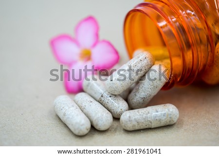 Herb capsules spilling out of a bottle.