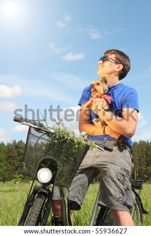 Young boy riding a bike with his dog on hands