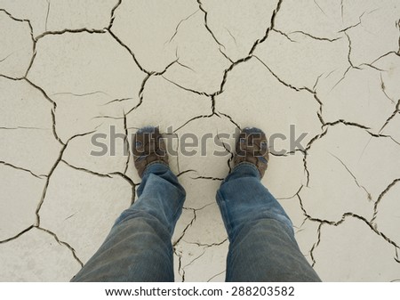 Feet in sandals on a cracked soil in dry season