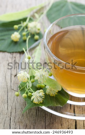 Chamomile tea with leaves on wood background