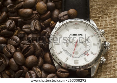 Silver watch with black leather belt and coffee beans on canvas