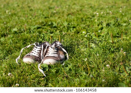 Summer scene of a pair of unlaced shoes in a grass field.