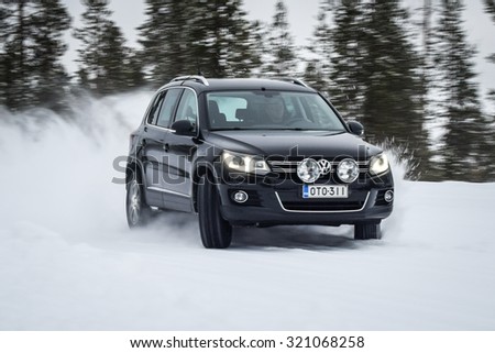 IVALO, FINLAND - February 15, 2015: Winter tire test is held at the proving ground. Test-driver performs snow handling test to determine the tire which provides the best grip on snow. SUV on display.