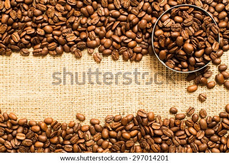 Top view on roasted whole coffee beans places horizontal and round metal bowl with coffee beans on sackcloth background