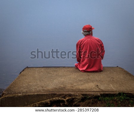 Man sitting enjoying a moment of peace at the lake on a foggy morning