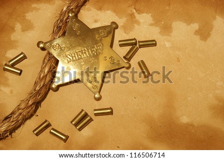 A sheriff badge and gun shells on some antique paper.