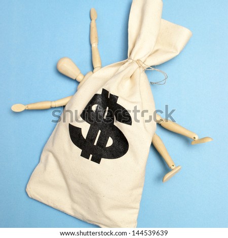 A dummy is crushed by a large bag of money.