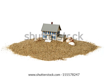 A closeup shot of a model house in the sand for waterfront property concepts.
