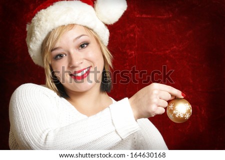 A beautiful woman holds a Christmas bauble as she gets ready to decorate.