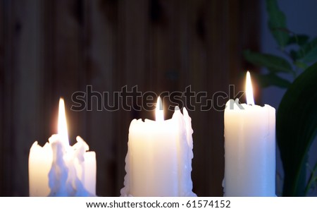 A set of three white candles burning in the night.
