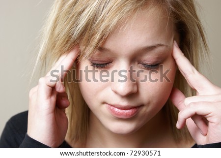 A young woman relieves the pain from her headache by putting pressure on her temples.