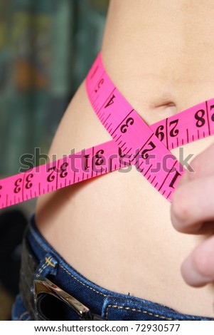 A woman measures her waistline to account for her ideal size and fitness.