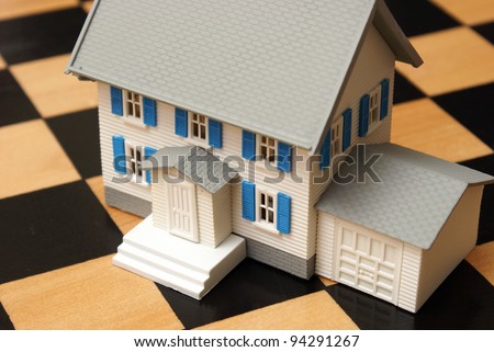 A real-estate strategy concept containing a model house and chess board.