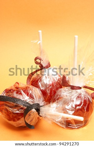Three red candy apples in plastic wrappers ready for treating the sweet tooth.