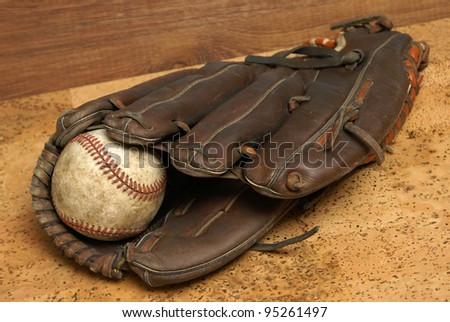 A low contrast image of a well used hardball and glove for those who love the sport of baseball.