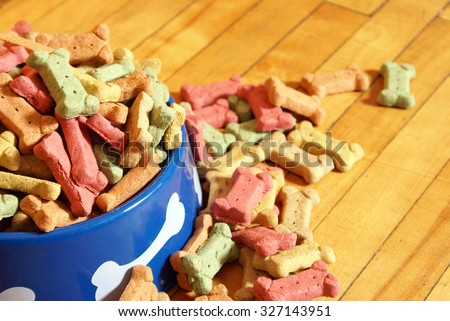 An over abundant supply of various dog treats flowing from a dish.