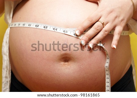 An expecting mother measures her babies belly weight gain.