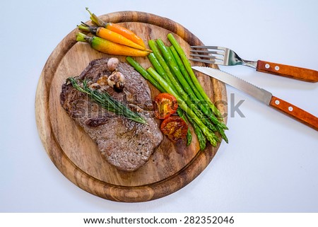 Beef ribeye steak with knife and fork for meat on cutting board