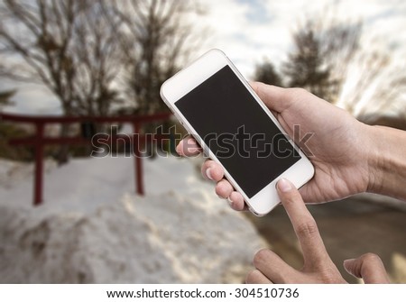 Woman holding smart phone or mobile phone with blank mobile.over blurred beautiful b sky on snow background for working online on vacation.