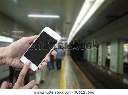 Woman holding smart phone or mobile phone with blank mobile.over blurred Subway tunnel background for working online on vacation.