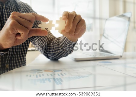 Business man hands connecting jigsaw puzzle. Business solutions, success and strategy concept. Close up photo with selective focus.
