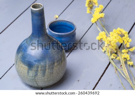 old vase and yellow flower on wood table