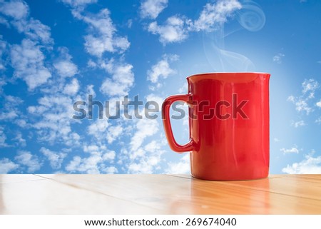 red coffee mug on wood table and blue sky