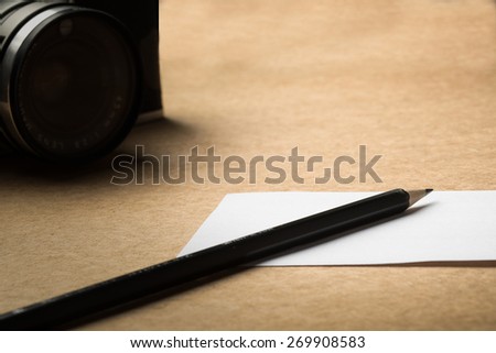 camera,pencil and white paper on desk