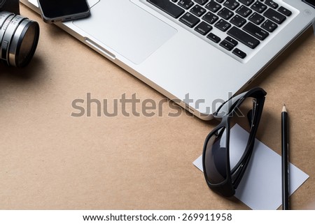 still life details, pencil, laptop, sunglasses, paper, camera ,smart phone on wood desk